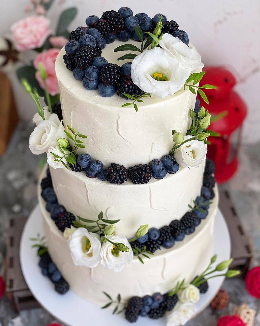 Белый трехъярусный торт украшенный ягодами